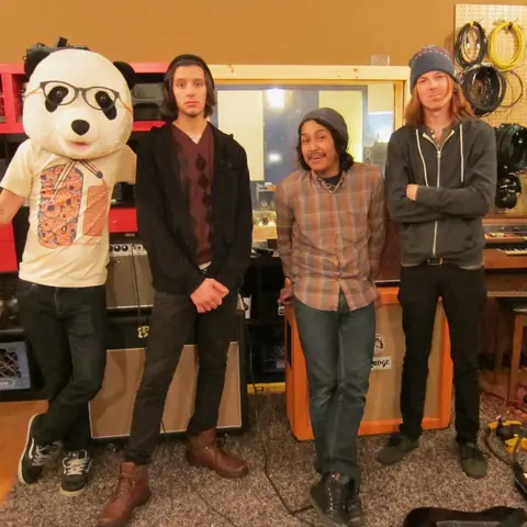 Someone in the Panda costume posing with a band, 2011