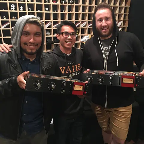 Three friends holding up new outboard gear, 2018