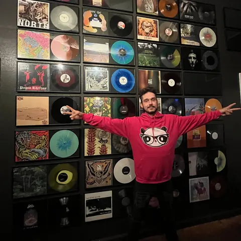 A guest with his arms spread wide in front of the Wall of Fame, 2021