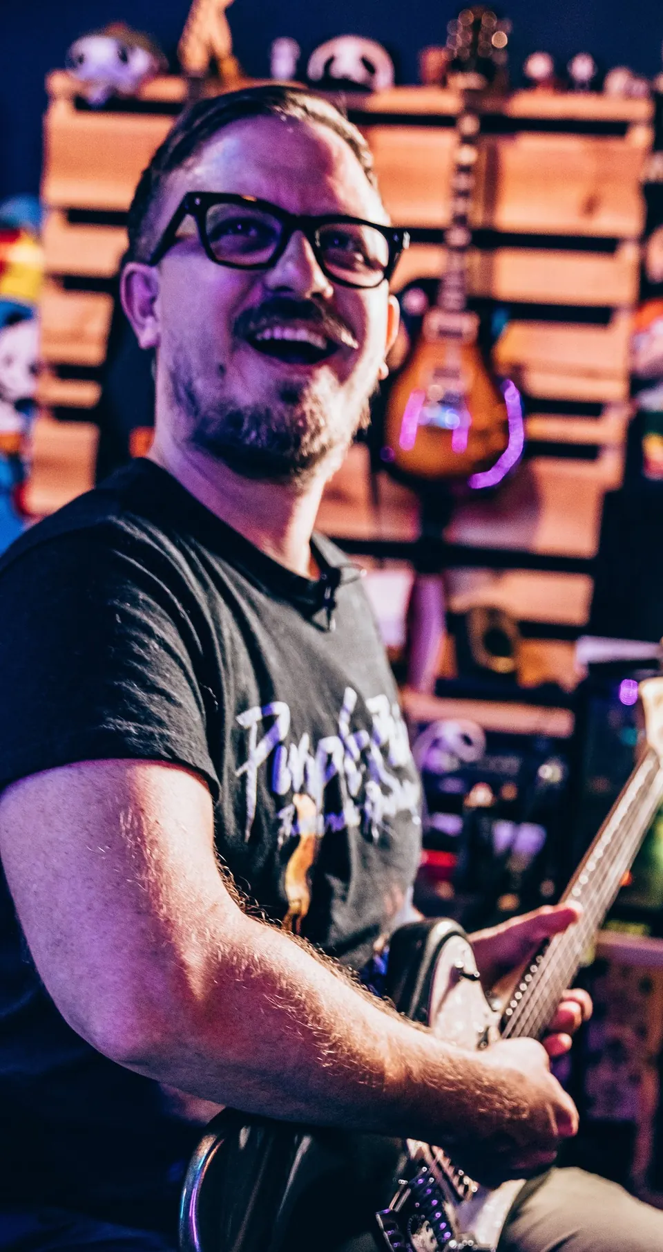 Sam Pura laughing mid-take with a guitar at the Panda West console