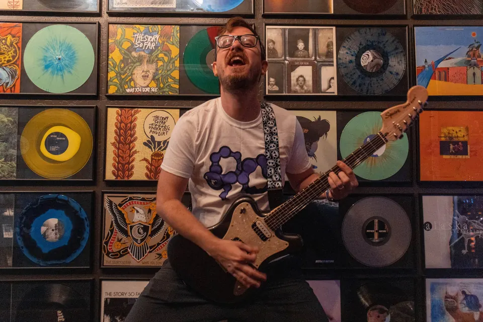 Sam Pura playing guitar in front of the Wall of Fame